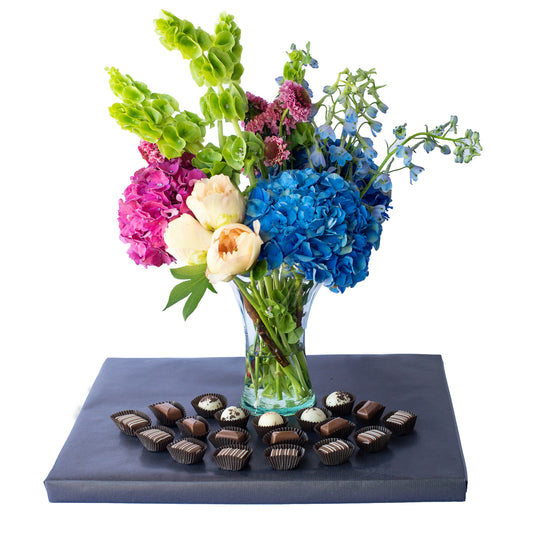 Fresh flower arrangement in vase with dairy Belgian Pralines